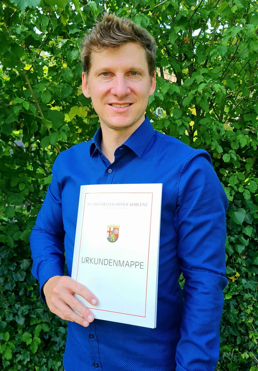 Dr. Till Wenz mit der Urkundenmappe der Bezirksärztekammer Koblenz